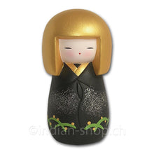 Japanische Kokeshi-Puppe mit goldfarbener Frisur und schwarzem Gewand mit Pflanzenmotiv