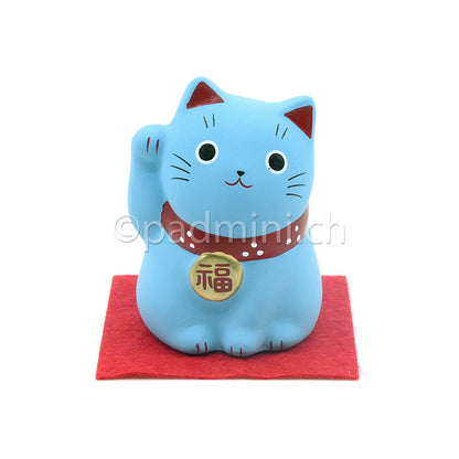 Japanische Maneki-Neko Glückskatze in Blau mit roten Details, erhobener Pfote und Glückszeichen auf der Halsplakette.