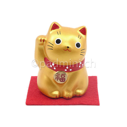 Japanische Maneki-Neko Glückskatze in Gold mit roten Details, erhobener Pfote und Glückszeichen auf der Halsplakette.