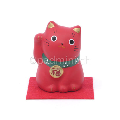 Japanische Maneki-Neko Glückskatze in Rot mit goldfarbenen Details, erhobener Pfote und Glückszeichen auf der Halsplakette.