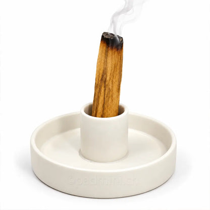 Weisser Keramikhalter für Palo Santo mit glimmendem Holzstück und feinem aufsteigendem Rauch.