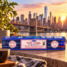 Satya New York Räucherstäbchen von Shrinivas Sugandhalaya (MUM) LLP in der 15-g-Packung vor der Skyline von New York mit Brooklyn Bridge bei Sonnenuntergang.
